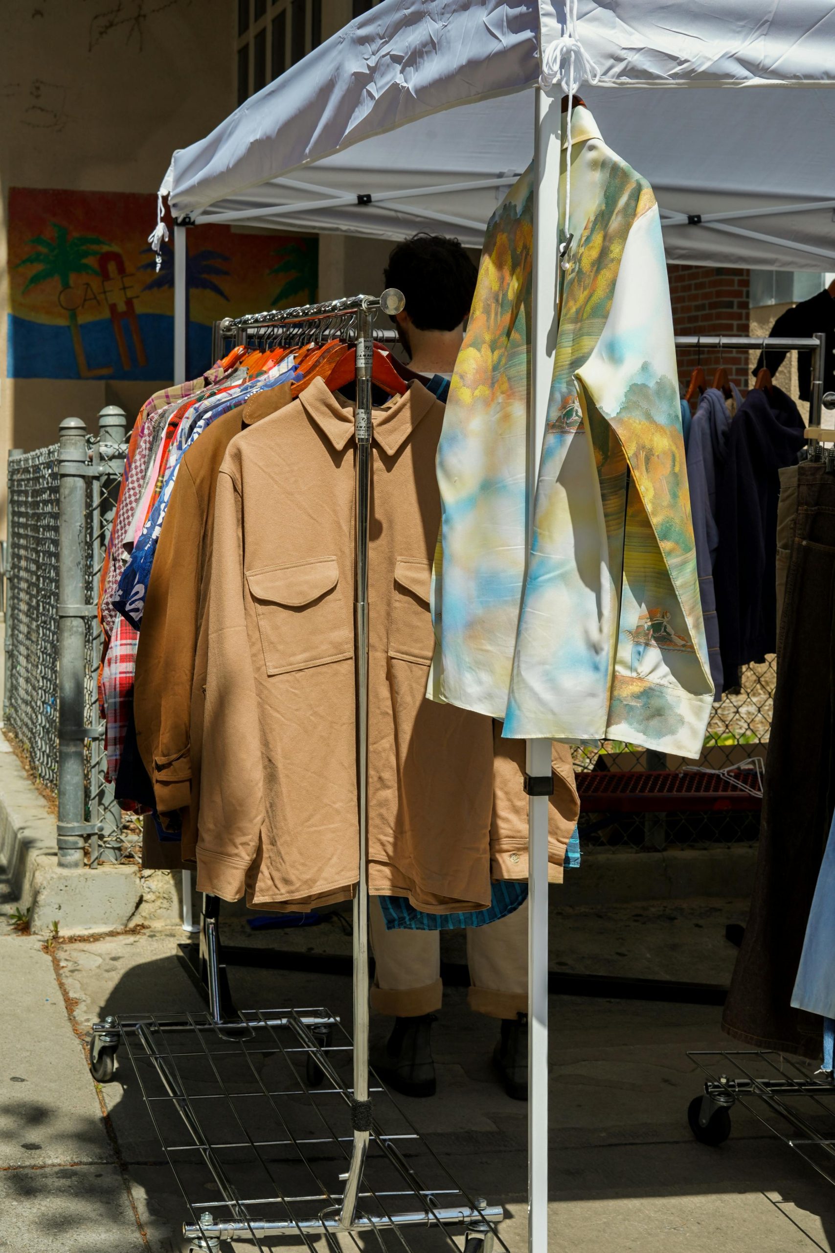 Farmers Market vs. Swap Meet: What’s the Difference? (And Why Saturday Swap Meets Has a Little of Both!) Outdoor market showcasing vintage clothes on racks under a sunny sky.